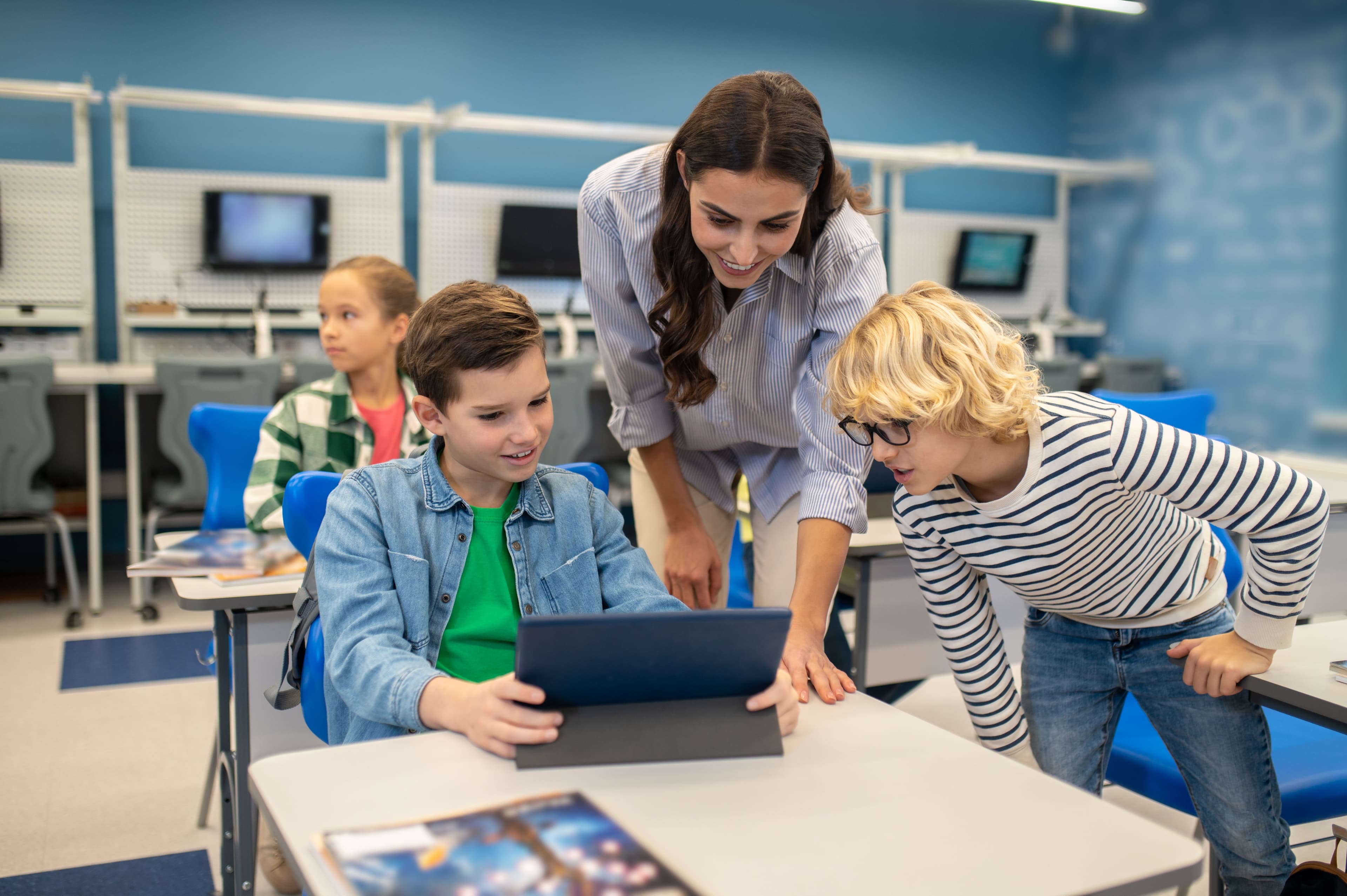 woman and two students looking at a laptop in a classroom